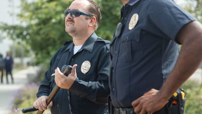 Deux policiers en uniforme à l'extérieur, équipés d'une matraque et d'une radio, regardant vigilants et prêts à servir.