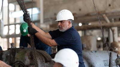 Travailleurs avec des casques manipulant des chaînes dans un environnement industriel en Libye.
