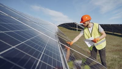 Technicien en EPI inspecte des panneaux solaires dans un champ d'énergie renouvelable, favorisant la durabilité.