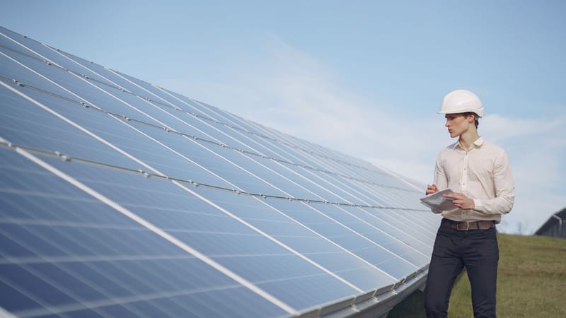 Un technicien avec un casque de protection inspecte des panneaux solaires, mettant en avant l'innovation en matière d'énergie renouvelable.