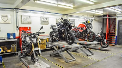 Atelier de réparation de motos présentant des motos Ducati, Honda et Kawasaki sur des supports.