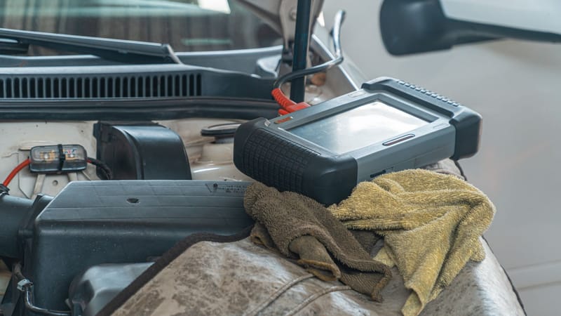 Gros plan d'un outil de diagnostic automobile sur un moteur dans un garage.