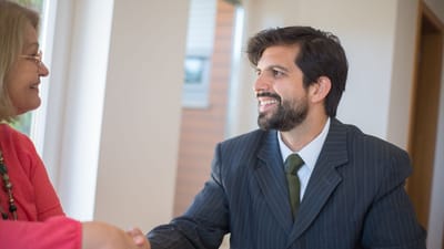 Agent immobilier professionnel scellant un accord avec un client senior à l'intérieur par une poignée de main.