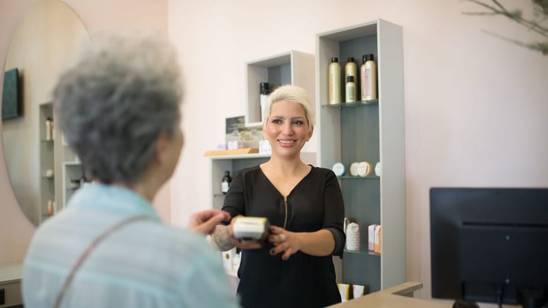 Coiffeur amical aidant un client avec le paiement dans un salon élégant.