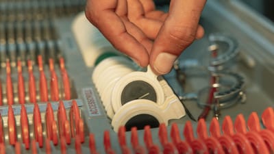 Vue détaillée de la main d'un optométriste choisissant une lentille dans un kit optique, mettant en avant la précision des soins oculaires.