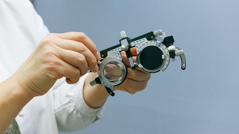 Gros plan sur des mains ajustant un cadre optique sur fond bleu, mettant en avant la précision et le professionnalisme.