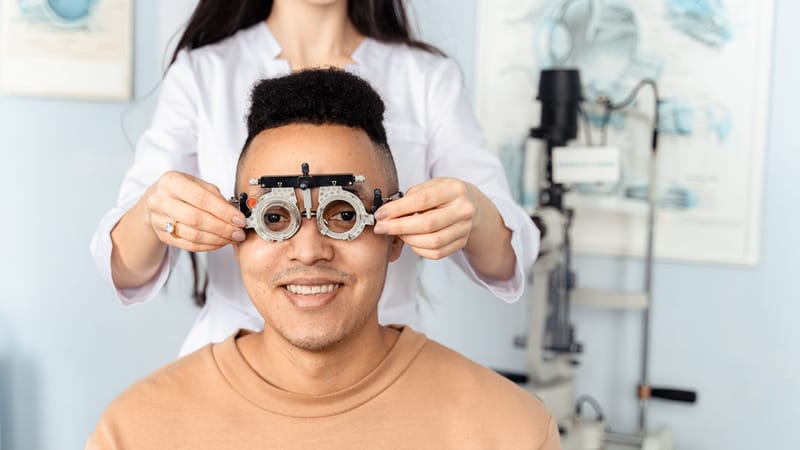 Un homme recevant un examen de la vue avec un phoroptère dans un cadre de clinique d'optométrie.