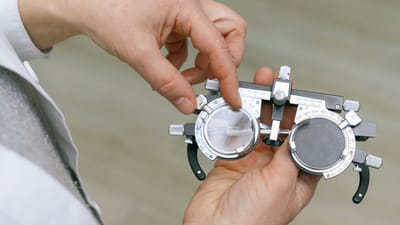 Gros plan d'un professionnel ajustant des lentilles d'essai pour un examen oculaire.