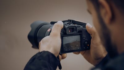 Plan détaillé d'un photographe réglant les paramètres d'un appareil photo numérique en extérieur.