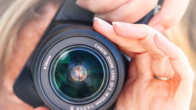 Gros plan d'une personne tenant un objectif d'appareil photo, axé sur la photographie.