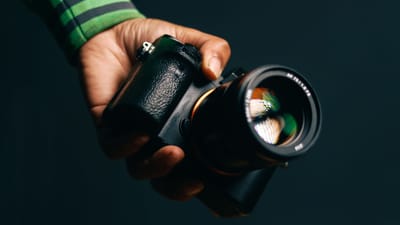 Une personne tenant un appareil photo devant un fond noir, parfait pour des concepts de photographie.