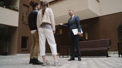 Un agent immobilier discute avec un couple dans une cour d'appartement moderne.