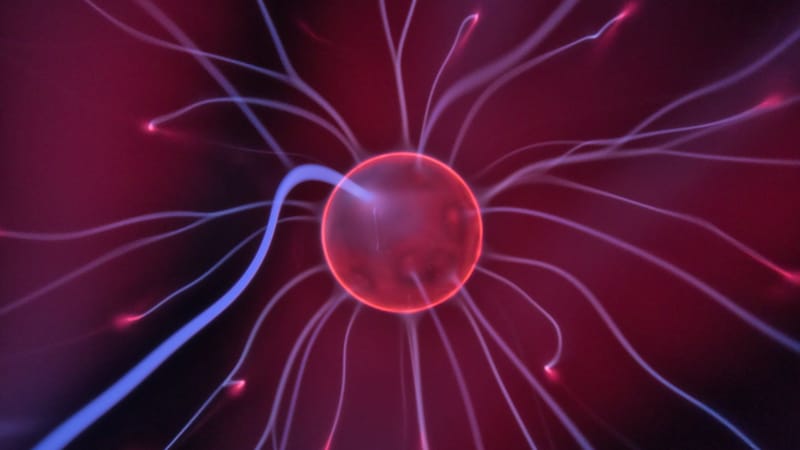Gros plan d'une boule plasma lumineuse avec des courants électriques colorés s'étendant vers l'extérieur.