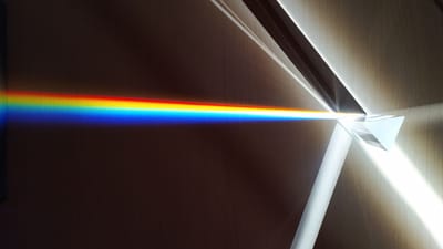 Un spectre coloré de lumière réfracté à travers un prisme en verre créant un effet arc-en-ciel.