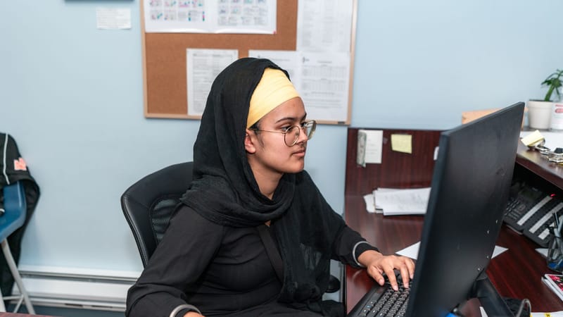 Femme du Moyen-Orient en hijab utilisant un ordinateur dans un cadre de bureau, concentrée sur son travail.