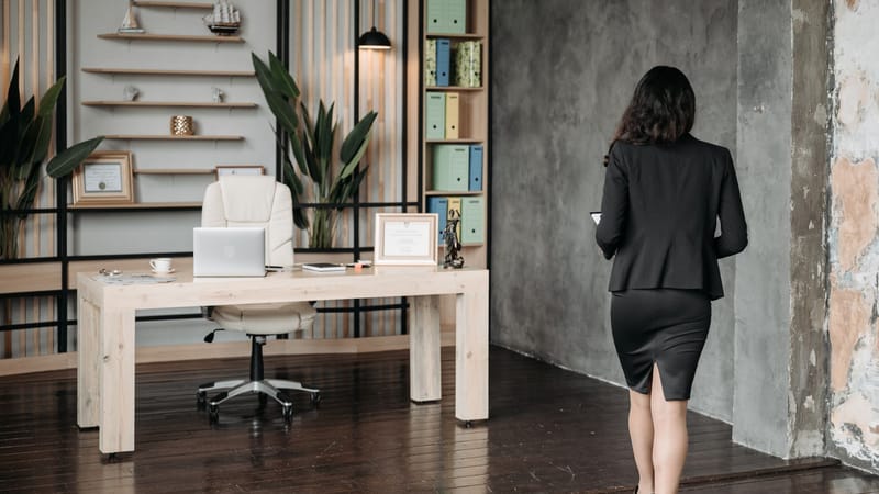 Femme d'affaires en tenue professionnelle marchant dans un espace de bureau moderne et élégant.