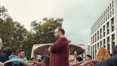 Groupe de personnes profitant d'une balade en bus à toit ouvert dans un cadre urbain par une journée nuageuse.