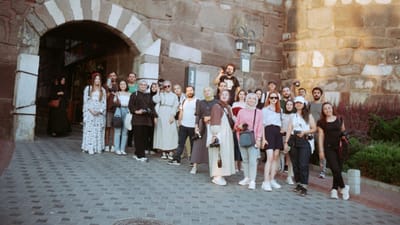 Un groupe de touristes pose devant une porte historique en pierre, capturant un moment de voyage mémorable.
