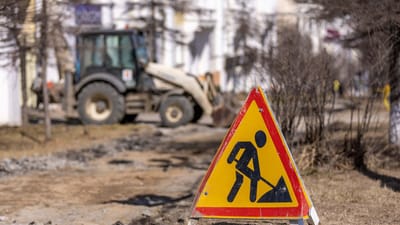 Un panneau de sécurité lumineux sur un chantier de construction routière avec des symboles de précaution visibles.