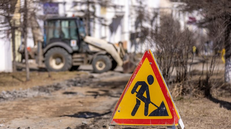 Un panneau de sécurité lumineux sur un chantier de construction routière avec des symboles de précaution visibles.