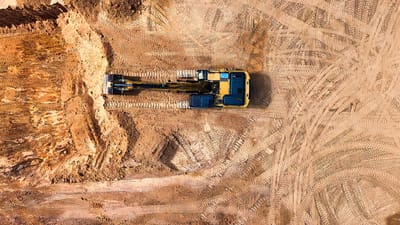 Photo aérienne d'une excavatrice travaillant sur un grand chantier de construction vide.