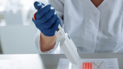 Gros plan d'un scientifique utilisant une pipette dans un laboratoire avec un accent sur les procédures stériles.