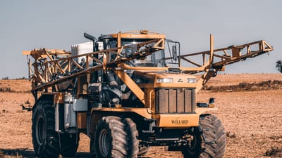 Un pulvérisateur agricole autoporté dans un vaste champ mettant en avant la technologie moderne de l'agriculture.