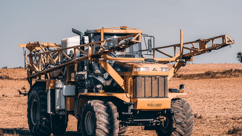 Un pulvérisateur agricole autoporté dans un vaste champ mettant en avant la technologie moderne de l'agriculture.