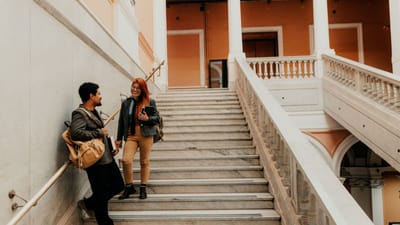 Deux étudiants universitaires discutent sur des escaliers en marbre élégants dans un bâtiment architectural.