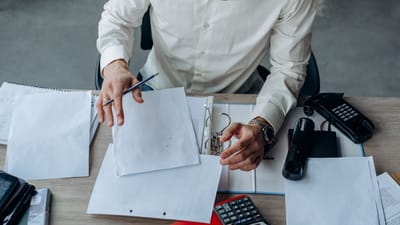 Un professionnel d'affaires organise des documents sur un bureau de bureau animé, mettant l'accent sur la productivité.
