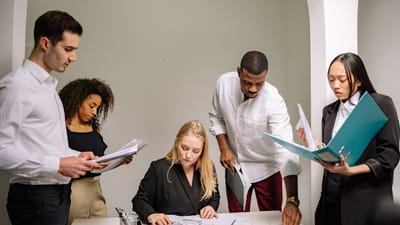 Équipe diversifiée travaillant ensemble dans un cadre de bureau, révisant des documents et collaborant sur des projets.