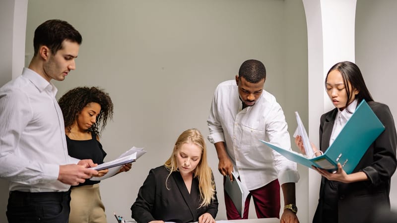 Équipe diversifiée travaillant ensemble dans un cadre de bureau, révisant des documents et collaborant sur des projets.