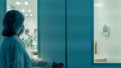 Un scientifique en tenue de protection entre dans un environnement de laboratoire stérile, garantissant la propreté.