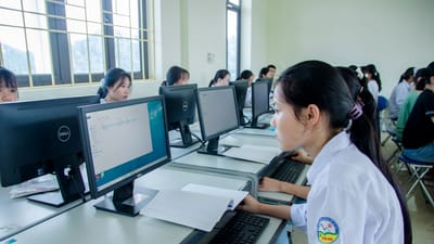 Groupe d'étudiants asiatiques travaillant ensemble dans un laboratoire informatique axé sur le travail d'équipe et la technologie.