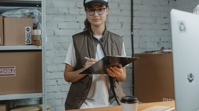 Jeune femme avec un clipboard dans un entrepôt, gérant l'inventaire avec précision.