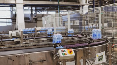 Des bouteilles d'eau en cours de traitement sur un transporteur automatisé dans un cadre d'usine moderne.