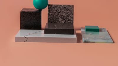 Un agencement géométrique minimaliste avec divers blocs texturés et une sphère sur un fond pêche.