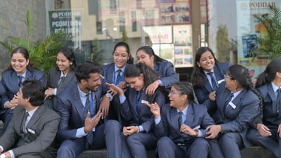 Des étudiants en commerce, vêtus de tenues formelles, profitent d'une conversation animée en plein air, illustrant ainsi leur esprit d'équipe et leur camaraderie.