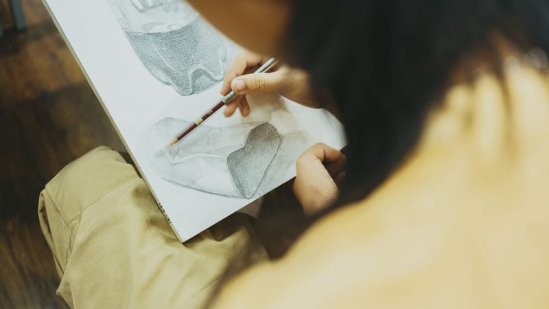 Gros plan d'une personne esquissant un dessin détaillé dans une salle de classe créative à Tokyo.