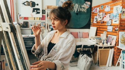 Une jeune femme concentrée peignant sur une toile dans un studio artistique créatif.