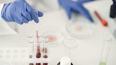 Un scientifique utilisant une pipette pour l'analyse chimique dans un laboratoire avec des éprouvettes et des gants de protection.