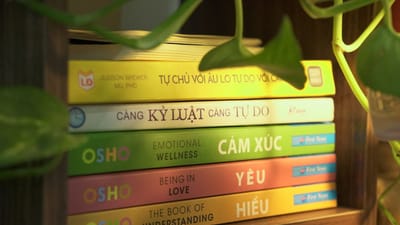 Une pile colorée de livres de développement personnel sur une étagère en bois, entourée d'une végétation luxuriante.