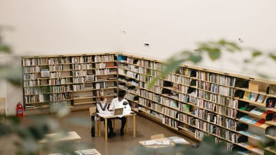 Étudiants étudiant ensemble à une bibliothèque avec des ordinateurs portables et des livres.