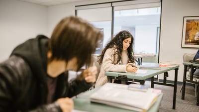Deux étudiants concentrés sur un examen dans une salle de classe pendant la journée.