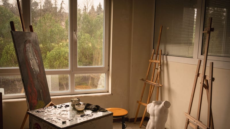 Atelier d'artiste confortable avec lumière naturelle, chevalets et une statue en forme de buste.
