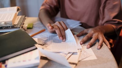 Une jeune femme étudiant intensément avec des manuels et des notes éparpillés sur une table.
