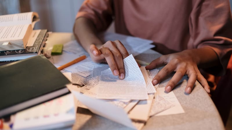 Une jeune femme étudiant intensément avec des manuels et des notes éparpillés sur une table.