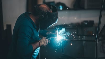 Un soudeur expérimenté travaille avec précision, créant des étincelles lors de la fabrication de métaux dans un atelier industriel.