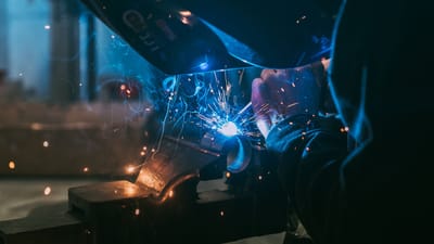 Gros plan d'un soudeur travaillant avec des étincelles, mettant en valeur l'artisanat industriel à Paris.