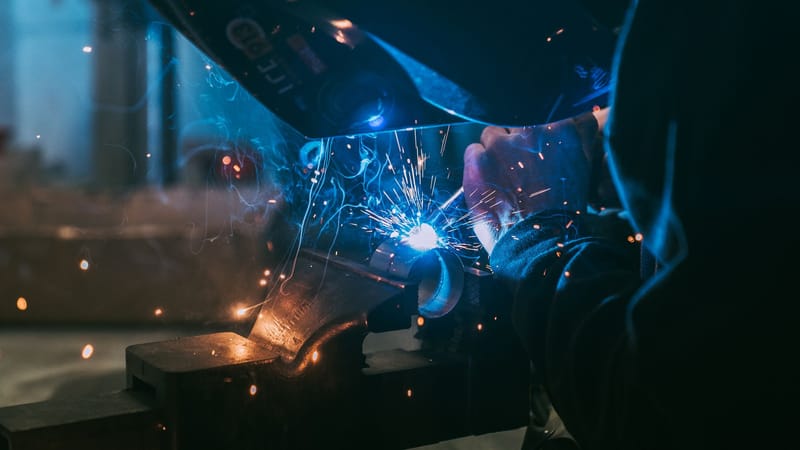 Gros plan d'un soudeur travaillant avec des étincelles, mettant en valeur l'artisanat industriel à Paris.